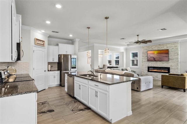 kitchen with a kitchen island with sink, sink, white cabinetry, and decorative light fixtures