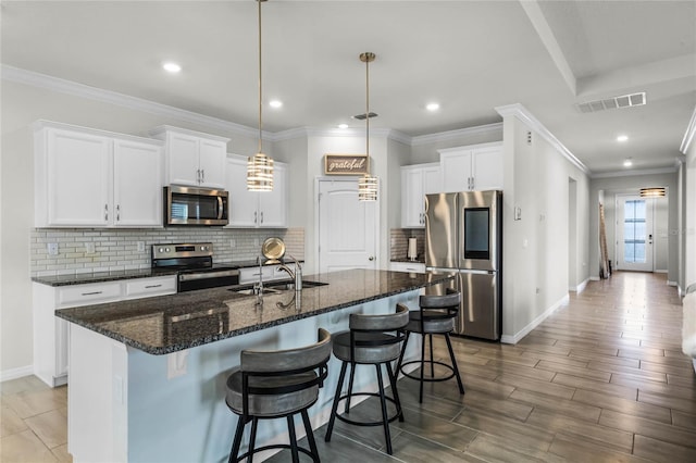 kitchen featuring an island with sink, appliances with stainless steel finishes, sink, and white cabinets