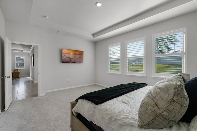 bedroom featuring a tray ceiling and light carpet