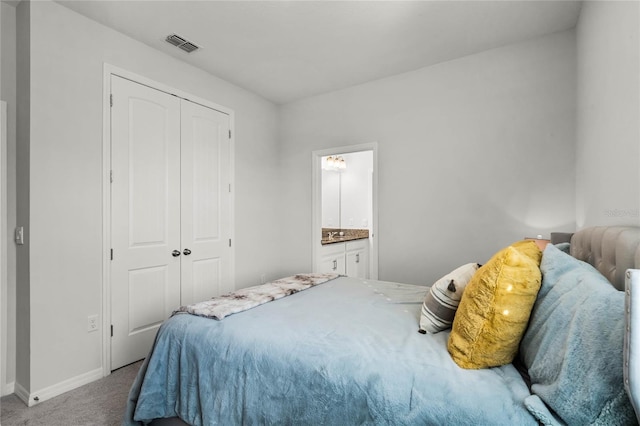 carpeted bedroom featuring ensuite bath and a closet