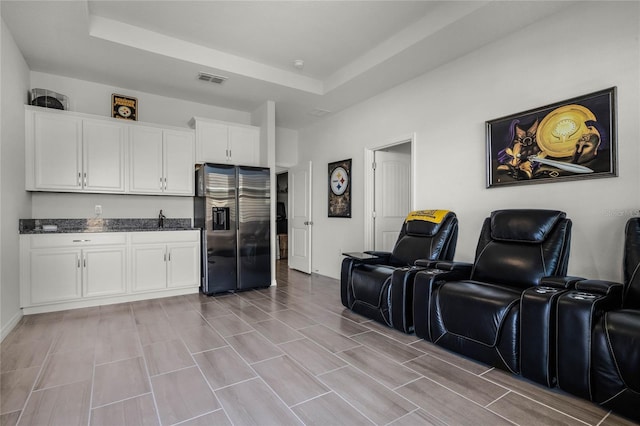 kitchen featuring stainless steel fridge, a raised ceiling, and white cabinets