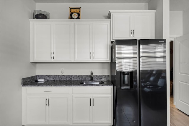 kitchen featuring dark stone counters, sink, stainless steel fridge with ice dispenser, and white cabinets