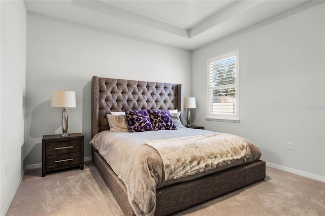 bedroom with light carpet and a tray ceiling