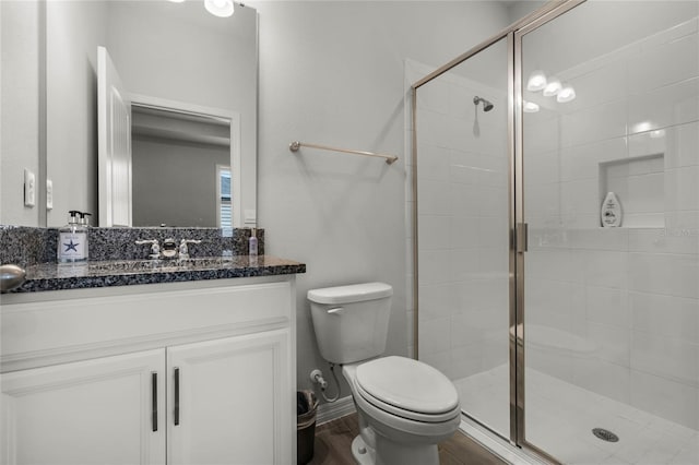 bathroom featuring a shower with door, vanity, hardwood / wood-style floors, and toilet