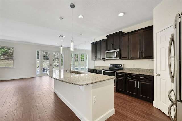 kitchen with sink, a breakfast bar area, hanging light fixtures, stainless steel appliances, and an island with sink