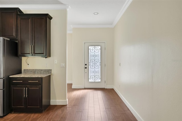 interior space featuring ornamental molding, wood-type flooring, stainless steel refrigerator, and dark brown cabinetry