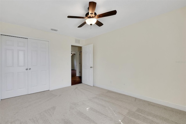 unfurnished bedroom featuring ceiling fan, light colored carpet, and a closet