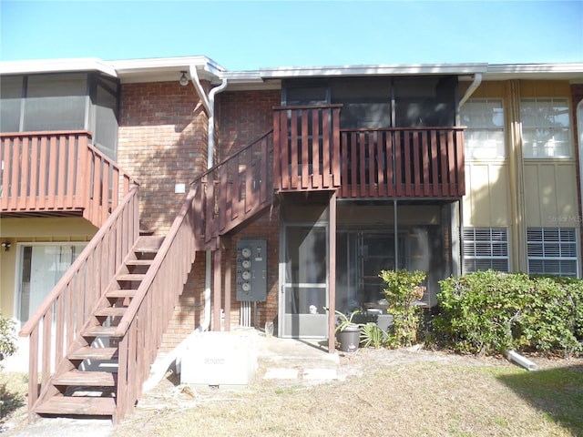 back of house with a sunroom, brick siding, and stairs