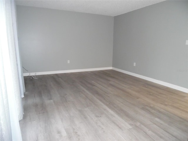 spare room featuring a textured ceiling, baseboards, and wood finished floors