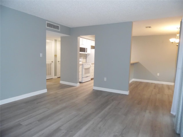 unfurnished room featuring baseboards, visible vents, and wood finished floors