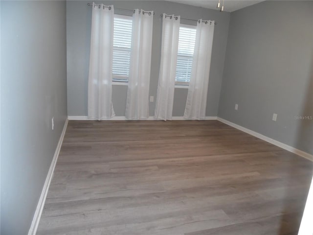 spare room featuring baseboards and wood finished floors