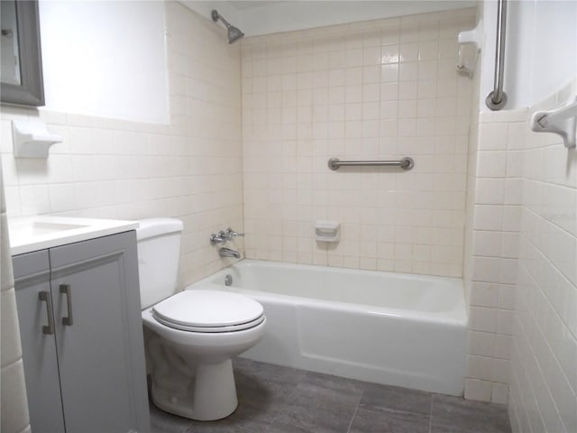 full bath with tile walls, toilet, vanity, shower / tub combination, and tile patterned floors