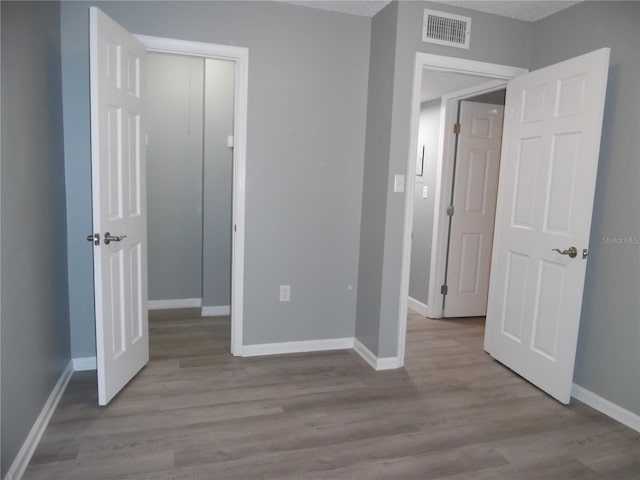 unfurnished bedroom featuring baseboards, visible vents, and wood finished floors