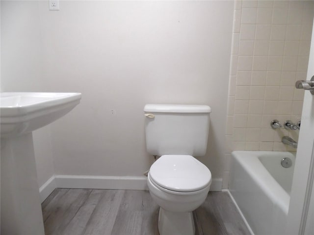 bathroom with baseboards, a sink, toilet, and wood finished floors