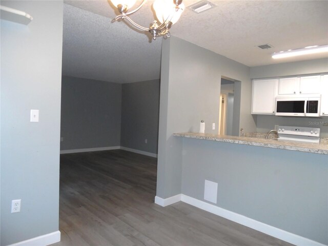 kitchen with a textured ceiling, white microwave, visible vents, and baseboards