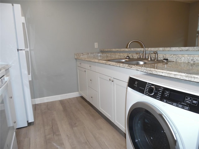 clothes washing area with light wood finished floors, baseboards, washer / clothes dryer, and a sink