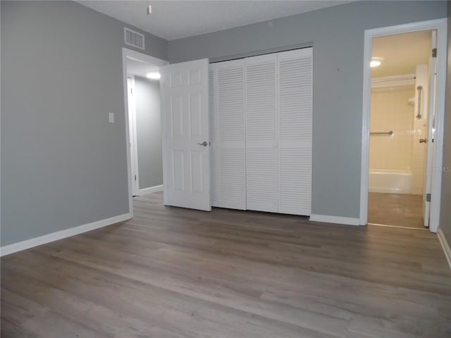 unfurnished bedroom with baseboards, a closet, visible vents, and wood finished floors