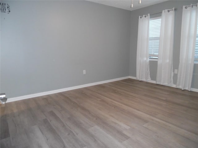 empty room featuring wood finished floors, a ceiling fan, and baseboards