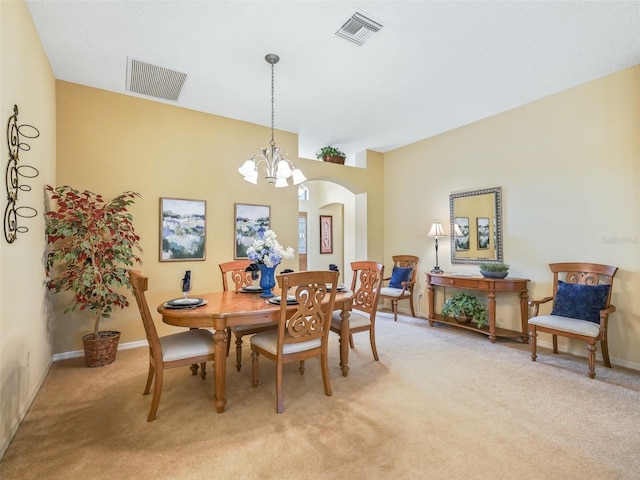 dining area featuring arched walkways, visible vents, and light carpet