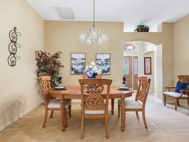 dining room with light carpet, an inviting chandelier, visible vents, and arched walkways