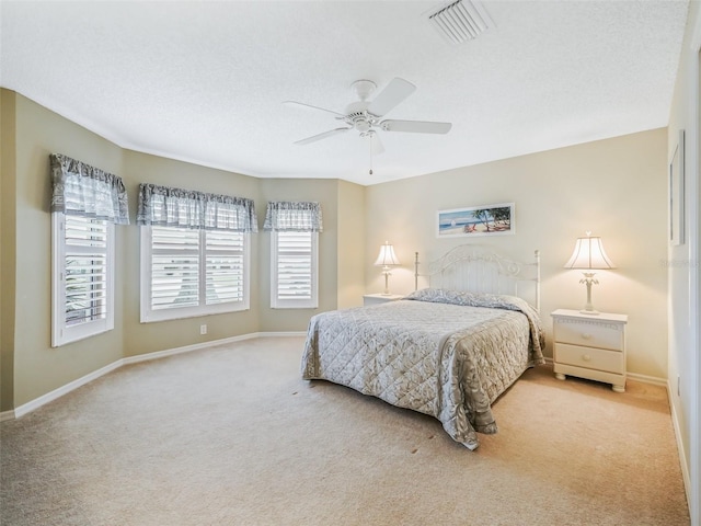 bedroom with light carpet, baseboards, visible vents, and a textured ceiling