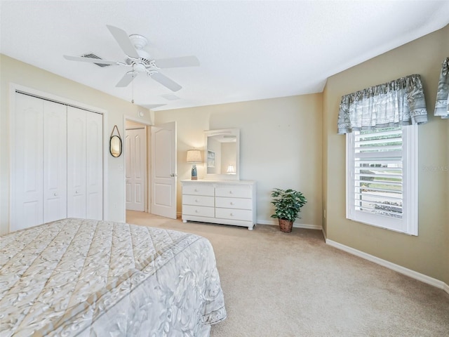 bedroom featuring baseboards, ceiling fan, a closet, and light colored carpet