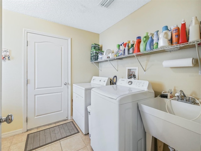 washroom featuring laundry area, visible vents, washing machine and clothes dryer, a textured ceiling, and a sink