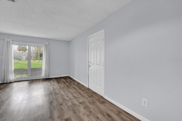 unfurnished room with light hardwood / wood-style flooring and a textured ceiling