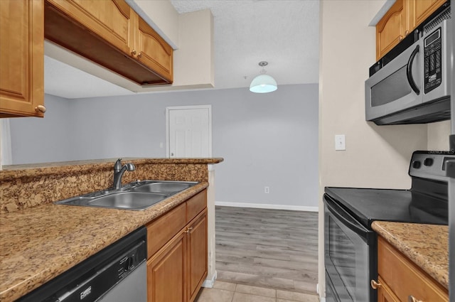 kitchen featuring sink, appliances with stainless steel finishes, light stone counters, a textured ceiling, and light wood-type flooring