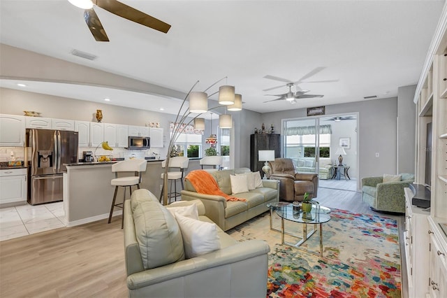 living room with vaulted ceiling, ceiling fan, and light hardwood / wood-style floors