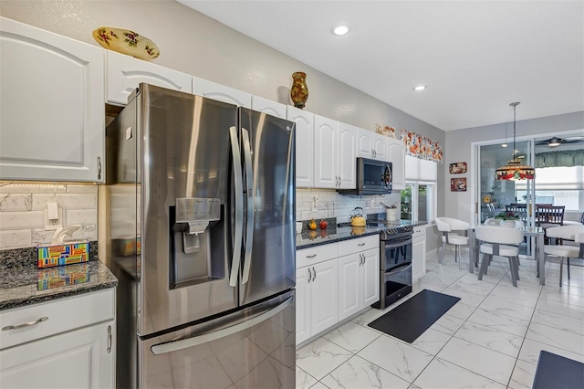 kitchen with white cabinetry, decorative light fixtures, appliances with stainless steel finishes, dark stone counters, and backsplash