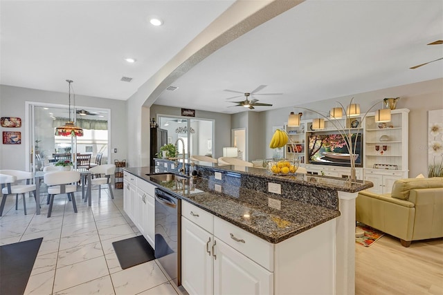 kitchen featuring sink, a center island with sink, stainless steel dishwasher, pendant lighting, and white cabinets