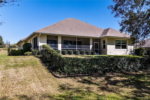 back of property with a lawn, a sunroom, and ceiling fan