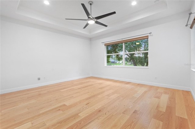 spare room featuring crown molding, ceiling fan, a tray ceiling, and light hardwood / wood-style flooring