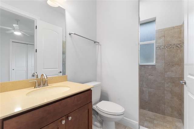 bathroom with vanity, ceiling fan, toilet, and a tile shower