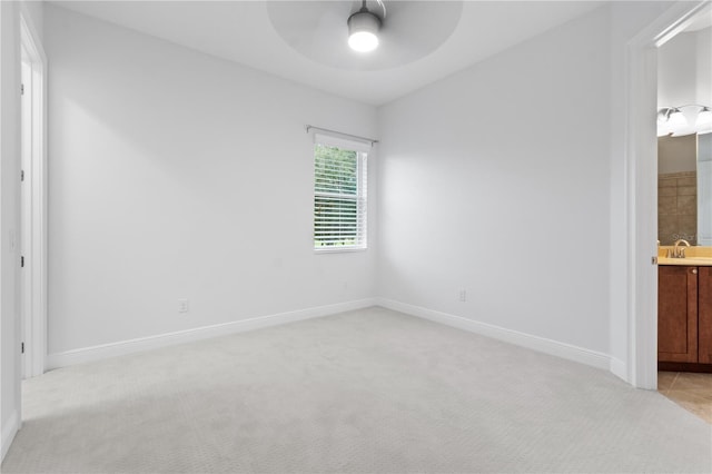 unfurnished bedroom featuring light carpet, sink, ensuite bath, and ceiling fan