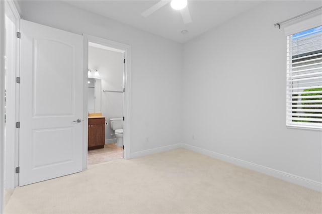 unfurnished bedroom with light carpet, ensuite bath, and ceiling fan