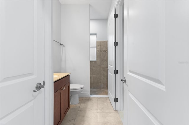 bathroom with vanity, a tile shower, tile patterned floors, and toilet