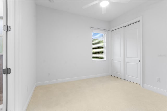 unfurnished bedroom with light carpet, ceiling fan, and a closet