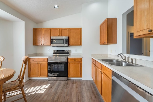 kitchen featuring lofted ceiling, sink, light hardwood / wood-style flooring, a textured ceiling, and stainless steel appliances