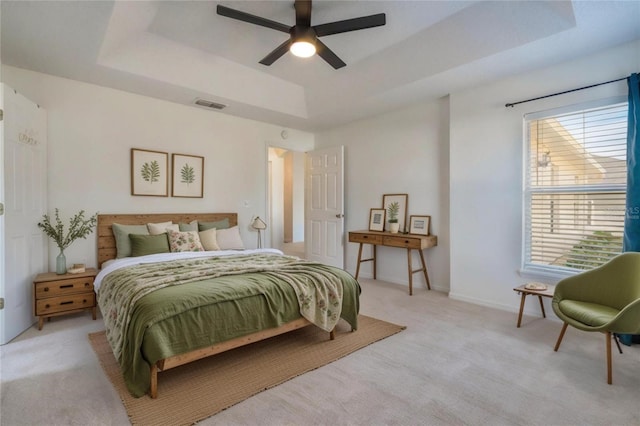 carpeted bedroom featuring ceiling fan and a tray ceiling