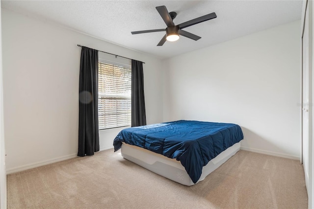 carpeted bedroom featuring ceiling fan and a textured ceiling