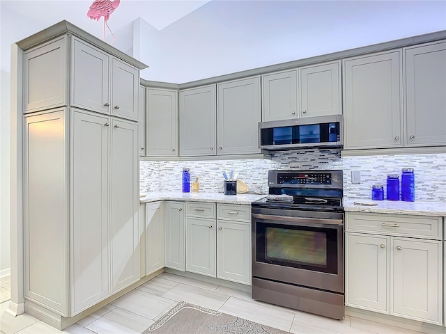 kitchen with light stone counters, appliances with stainless steel finishes, and tasteful backsplash