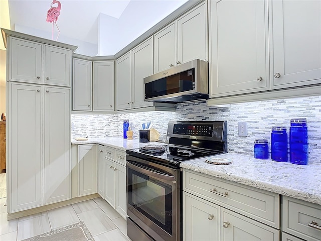 kitchen featuring tasteful backsplash, light stone countertops, appliances with stainless steel finishes, and gray cabinets