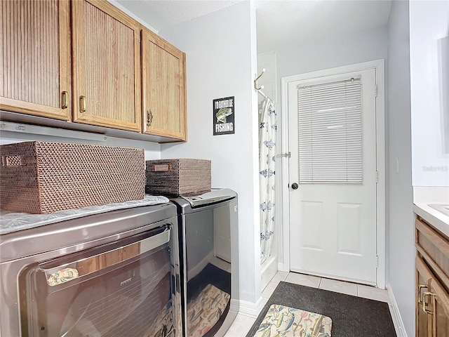 laundry area featuring light tile patterned flooring, cabinets, and washer and dryer