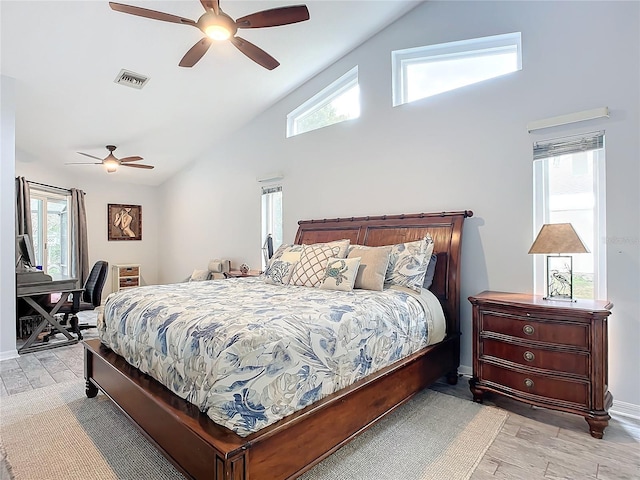 bedroom featuring ceiling fan, high vaulted ceiling, multiple windows, and light wood-type flooring