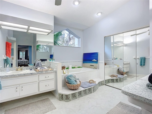 bathroom with vanity and tiled tub