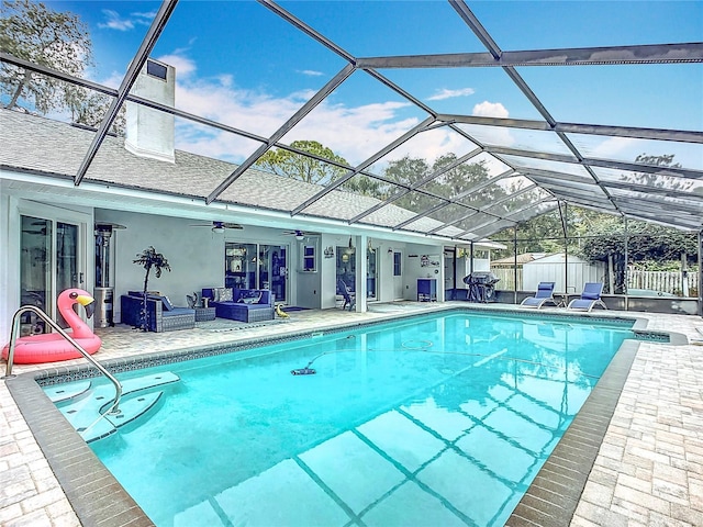 view of pool featuring a lanai, ceiling fan, outdoor lounge area, a patio area, and a storage unit