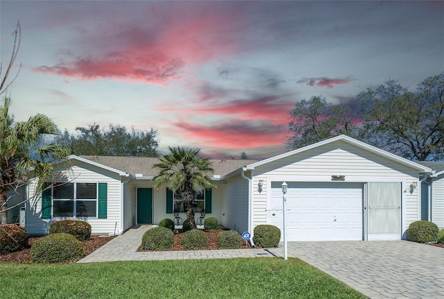 single story home featuring a garage, decorative driveway, roof with shingles, and a front lawn