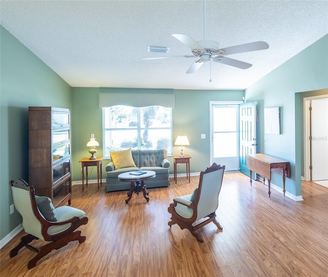 living room featuring light wood-style floors, lofted ceiling, a healthy amount of sunlight, and a textured ceiling